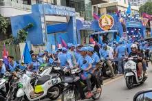 Viele Menschen mit blauen T-Shirts und blauen Cappys auf Motorrollern