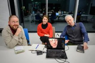 Die Mitglieder der Jury des Friedensfilmpreises 2022 sitzen an einem Tisch, ein Mitglied ist auf einem Laptop-Bildschirm zu sehen